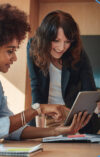 2 smiling women look at the onOffice Marketplace of the onOffice enterprise software on their tablet.