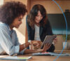 2 smiling women look at the onOffice Marketplace of the onOffice enterprise software on their tablet.